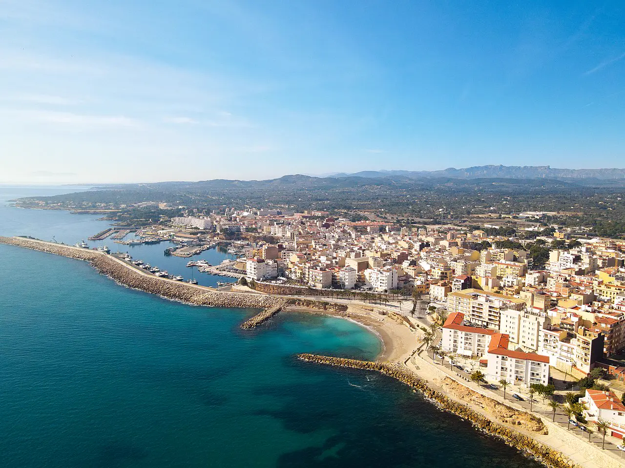 Vista aérea de la Platja de l'Alguer con arena, paseo marítimo, puerto y el mar de L'Ametlla de Mar